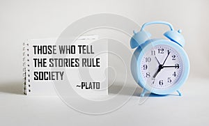 Those who tell stories rule society, Plato quotes the ancient Greek philosopher. Inspirational handwriting on notepad on white