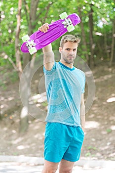 Who want to learn extreme trick. Guy carries penny board ready to ride. Man serious face carries penny board park nature