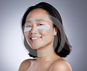 Who wants puffy eyes. a young woman wearing an eye mask against a grey background.