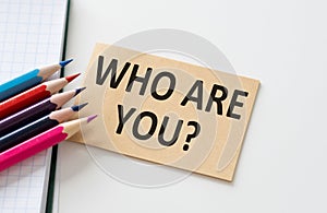 Who Are Yous text on a card on a white background next and colored pencils.