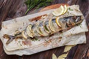 Whole baked mackerel or scomber fish with lemon on paper photo