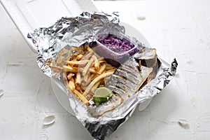 Whole baked sea bream, served with potato fries and red cabbage salad, in a takeaway box. Fish and chips lunch set.