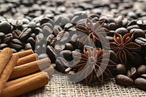 Whole bean coffee with star aniseas and cinnamon sticks on light burlap photo