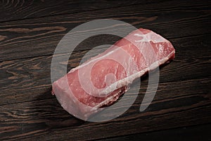 Whole boneless pork loin without fat. Pork tenderloin on a dark background