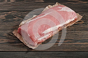 Whole boneless pork loin without fat. Pork tenderloin on paper on a dark background