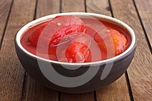 Whole canned tomatoes in brown bowl