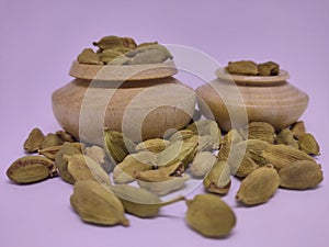 Whole cardamon seeds in traditional spice pot. White background