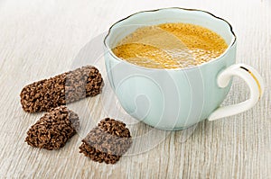 Whole cereal candy in glaze, pieces of candy, cup with black coffee on table