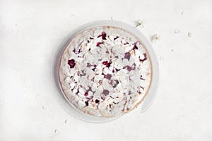 Whole cherry cake with almond petals and sugar powder on white background with cherry flowers
