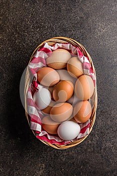 Whole chicken eggs in basket on black table. Top view