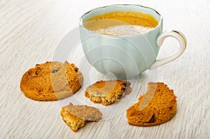 Whole cookie with chocolate, coffee in blue cup, broken cookie on wooden table