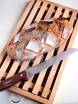 Whole country loaf on a cutting board with a bread knife