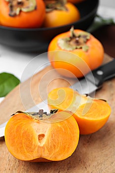 Whole and cut delicious ripe persimmons on table, closeup