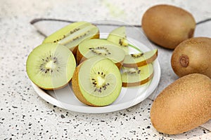 Whole and cut fresh kiwis on white table with pattern, closeup