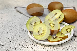 Whole and cut fresh kiwis on white table with pattern. Space for text
