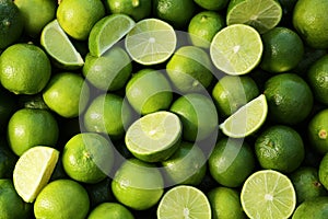 Whole and cut fresh ripe green limes as background, top view