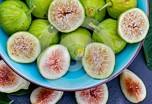 Whole and cut green figs, with fig leaves.