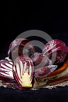 Whole And Cut In Half Fresh Red Cabbage In A Wooden Plate on Dark Background