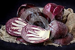 Whole And Cut In Half Fresh Red Cabbage In A Wooden Plate on Dark Background