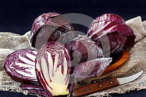 Whole And Cut In Half Fresh Red Cabbage In A Wooden Plate on Dark Background