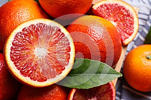 Whole and cut ripe red oranges with green leaf, closeup