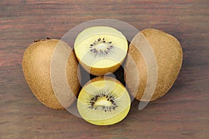 Whole and cut ripe yellow kiwis on wooden table, flat lay