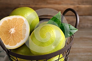 Whole and cut sweetie fruits in metal basket, closeup photo