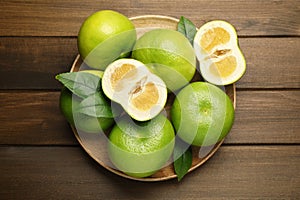 Whole and cut sweetie fruits on wooden table, top view
