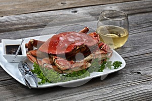 Whole Dungeness crab in dinner setting with wine on wooden table in close up layout