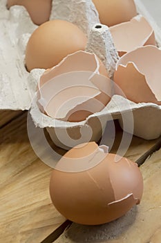 Whole eggs and an empty shell together in a tray. Broken eggs. Chicken egg shells in the tray. There is only broken