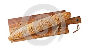 Whole fresh baked loaf wheat baguette bread with crumbs and seeds on wooden cutting board isolated on white background