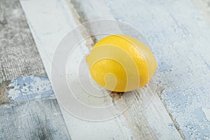 A whole fresh lemon with water droplets on a wooden table