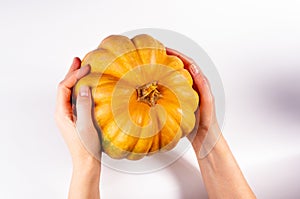 Whole fresh orange big pumpkin in female hands on white background, closeup. Organic agricultural product, ingredients