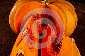 Whole fresh orange big pumpkin and slice of pumpkin on black background, closeup. Organic agricultural product