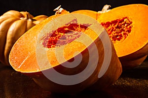 Whole fresh orange big pumpkin and slice of pumpkin on black background, closeup. Organic agricultural product