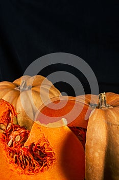 Whole fresh orange big pumpkin and slice of pumpkin on black background, closeup. Organic agricultural product