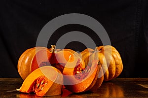 Whole fresh orange big pumpkin and slice of pumpkin on black background, closeup. Organic agricultural product