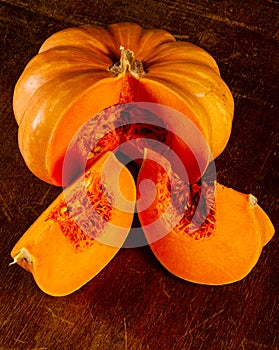 Whole fresh orange big pumpkin and slice of pumpkin on black background, closeup. Organic agricultural product