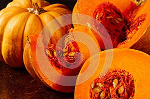 Whole fresh orange big pumpkin and slice of pumpkin on black background, closeup. Organic agricultural product