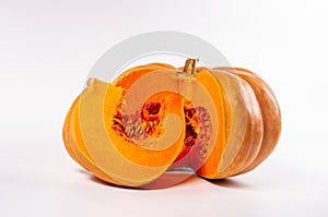 Whole fresh orange big pumpkin and slice of pumpkin on white background, closeup. Organic agricultural product