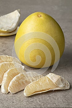 Whole fresh Pomelo and peeled pomelo slices close up