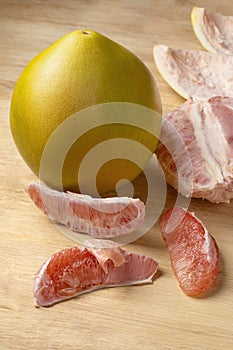 Whole fresh red Pomelo and peeled pomelo slices close up