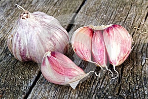 Whole garlic with broken bulb and pink cloves on rustic wooden b