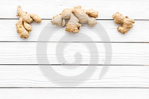Whole ginger roots on white wooden background top view space for text
