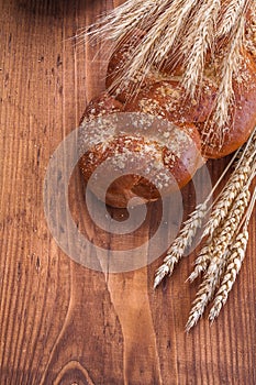 Whole grain bread with wheat ears on old wooden