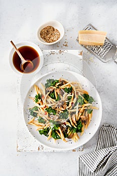 Whole grain pasta with kale, mushrooms, parmezan cheese in white plate on light background photo