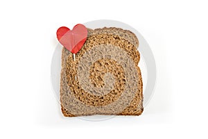 Whole grain sandwich bread slice with heart pin, on white background.