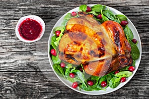 Whole grilled chicken on white dish with salad and cranberry