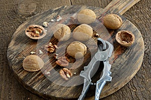 Walnuts on an old wooden board with a nutcracker.