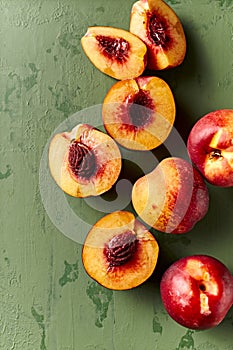 Whole and halved nectarines on rustic painted background